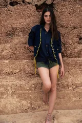 Camisa negra de lino con cuello clásico, manga larga y cierre frontal con botones. Presenta un bordado con un caballito, un sol y la bandera de Uruguay en el frente.