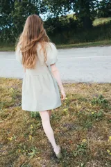 Vestido corto de algodón a cuadros en tonos beige y verde claro. Tiene cuello redondo con abertura y lazos, mangas cortas abullonadas y falda con leve vuelo.