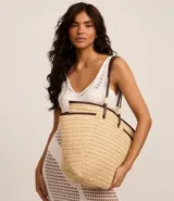 Bolso de playa tipo tote de paja natural con asas de cuero sintético marrón, forro interior y bolsillo interno.
