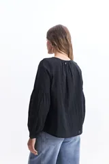 Blusa blanca de manga larga con detalle de tablas en el frente y puños.