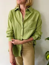 Camisa verde de lino, corte amplio y largo, con cuello clásico y mangas largas.