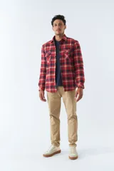 Sobrecamisa de algodón para hombre con interior de corderito, estampado a cuadros en tonos negro, blanco y azul. Tiene cierre de botones, bolsillos tipo cartera y logo en goma. El modelo usa talle M.