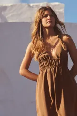 Vestido midi color marrón confeccionado en tejido fluido, con escote pico y tirantes finos cruzados en la espalda ajustables con lazada.