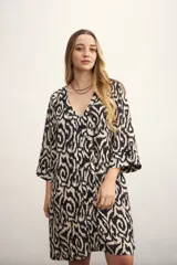 Vestido corto con estampado abstracto en blanco y negro, escote en V y mangas 3/4 acampanadas.