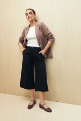 Pantalón capri color beige de algodón, con corte acampanado, bolsillos laterales tipo cargo y cintura con cordón ajustable.