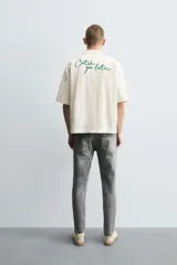 Pantalón de jean negro ajustado al cuerpo desde la cintura hasta el tobillo, de tiro medio y tejido elástico. Diseño de cinco bolsillos con lavado efecto roto y cierre frontal con cremallera y botón.