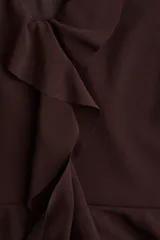 Musculosa de tejido liviano color marrón oscuro, con escote en V pronunciado adornado con volados en cascada en el frente. Posee breteles anchos y un bajo con doble capa de volados.