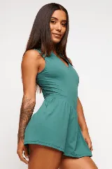 Vestido deportivo color verde con logo bordado en blanco en el pecho. Diseño sin mangas, con cuello mao y cierre parcial con botones. Falda con corte evasé y short interno.