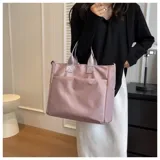 Bolso tipo tote color celeste con correa larga verde y asas cortas.