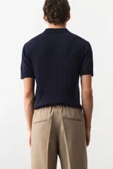Remera polo de manga corta color azul marino en punto acanalado de mezcla de algodón con cuello y medio cierre. Remate acanalado de raya fina en mangas y bajo. Corte ajustado que realza el contorno del cuerpo creando una silueta entallada.