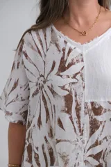 Blusa blanca con estampado de hojas marrones, de corte holgado y mangas cortas.