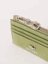 Tarjetero de cuero vacuno color bordó con aplique metálico de flor y tiracierre con diseño exclusivo.