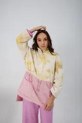 Buzo oversize color crema con estampado de hojas en tonos verde y amarillo, cuello alto con medio cierre metálico y jareta en la cintura para ajustar.