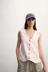 Chaleco color rosa pálido con botones marrones, escote en V y sin mangas.