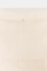 Mono corto color crema, confeccionado en lino. Presenta escote recto, hombros descubiertos, detalle de drapeado y cierre trasero con cremallera oculta.