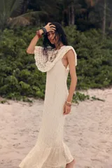 Vestido largo color crudo, tejido a crochet con diseño calado. Tiene cuello redondo, mangas cortas con volados y forro interior.