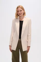 Blazer color beige de lino, con cuello solapa, corte holgado y bolsillos laterales.