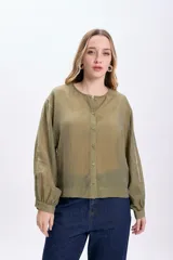 Camisa casual manga larga color verde oliva, de tela traslúcida con textura sutil. Tiene cuello redondo, cierre frontal con botones y mangas largas con puños elásticos.