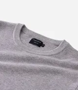 Suéter de punto color gris, con cuello redondo, manga larga y textura maquinetada.