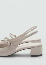 Zapato destalonado color beige con efecto charol, taco bloque de 5 cm, punta redonda y tira con hebilla.