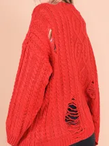 Cárdigan tejido de punto grueso color celeste con diseño trenzado y roturas. Tiene cuello en V, cierre frontal con botones y mangas largas.