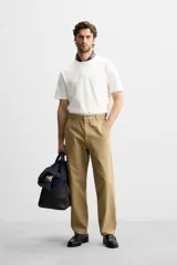 Pantalón chino color beige de corte recto, con cintura ajustable con cordón interior y trabillas laterales. Tiene bolsillos frontales y traseros de vivo.