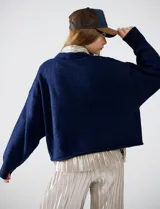 Buzo de tejido melange azul oscuro, con cuello redondo y mangas largas, corte cropped y calce holgado.