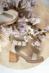 Sandalias de cuero color crudo, con tira ancha sobre los dedos, pulsera con hebilla al tobillo y taco cuadrado de madera.