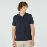 Remera polo azul marino de piqué de algodón con estampado de pequeños detalles geométricos en blanco y rojo.