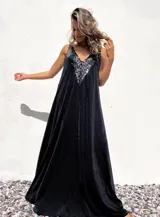 Vestido largo negro con escote en V y breteles finos. Presenta apliques de lentejuelas negras en el escote.
