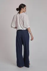 Camisa blanca con estampado de cruces, cuello mao y mangas 3/4 con detalle de pliegues en los hombros. Cierre frontal con botones.