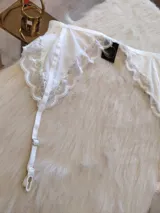 Portaligas blanco de lycra con detalles de encaje y tiras regulables.