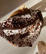 Riñonera con estampado animal, con detalles en cuero color chocolate y correa regulable.