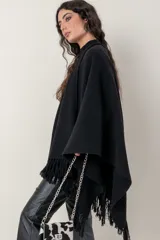 Ruana de punto color negro, modelo Esteña, con diseño abierto y terminación de flecos en los bordes.