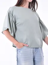 Blusa negra de mangas cortas con volados y escote redondo.