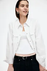 Musculosa blanca con breteles anchos, cierre oculto lateral y escote redondeado pronunciado adelante y atrás. Modelo con pinzas en el busto y cintura entallada con costuras visibles adelante y atrás. Parte superior forrada.