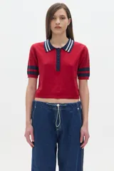Remera polo corta color rojo con cuello y mangas con rayas azul marino y blanco.