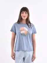 Remera de manga corta, cuello redondo y calce holgado, color azul claro jaspeado, con estampado frontal de hojas de ginkgo en tonos rosados, blancos y grises con detalles dorados.