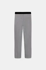 Pantalón tobillero celeste con tiro medio, cintura elástica en la espalda, bolsillos delanteros y falsos bolsillos de vivo en la espalda. Tiene aberturas laterales en el bajo y cierre frontal con cremallera, botón interior y gancho.