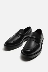 Mocasín de vestir negro con detalle de antifaz en el empeine y suela a tono con ligero tacón.