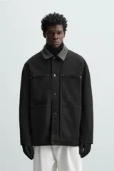 Parka negra de algodón con cuello solapa de cuero sintético, corte recto, acolchada, con bolsillos de parche y cierre frontal con botones.