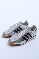 Championes Adidas SL 72 plateados con detalles en azul marino y suela de goma marrón.
