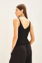 Musculosa negra de tejido rib con lentejuelas bordadas a tono, de calce al cuerpo y escote en V.