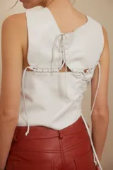 Top blanco de cuero ovino con cuello babero y detalles artesanales en pasamanería.