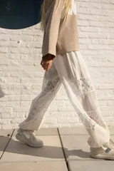 Pantalón amplio color crudo confeccionado en lino, con cintura elastizada y detalle de encaje en las piernas.