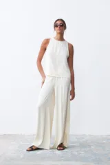 Pantalón palazzo color crudo, de tiro alto y corte holgado.