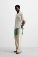 Camisa negra de corte relaxed fit, confeccionada en tejido con mezcla de modal. Tiene cuello bowling, manga corta, bolsillo de parche en el pecho y cierre frontal con botones.
