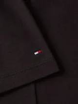 Vestido midi negro de algodón con cuello redondo, mangas cortas y corte evasé. Presenta detalles de botones dorados en los hombros y logo de la marca bordado en la manga.