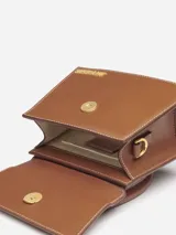 Bolso mini de cuero color marrón, con asa corta reforzada y correa larga extraíble. Cierre magnético, bolsillo interior y herrajes metálicos dorados.