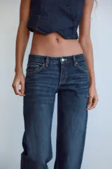 Jeans de mezclilla azul oscuro con efecto lavado, tiro bajo y pierna ancha extra larga. Modelo de cinco bolsillos con cierre frontal de cremallera y botón metálico.
